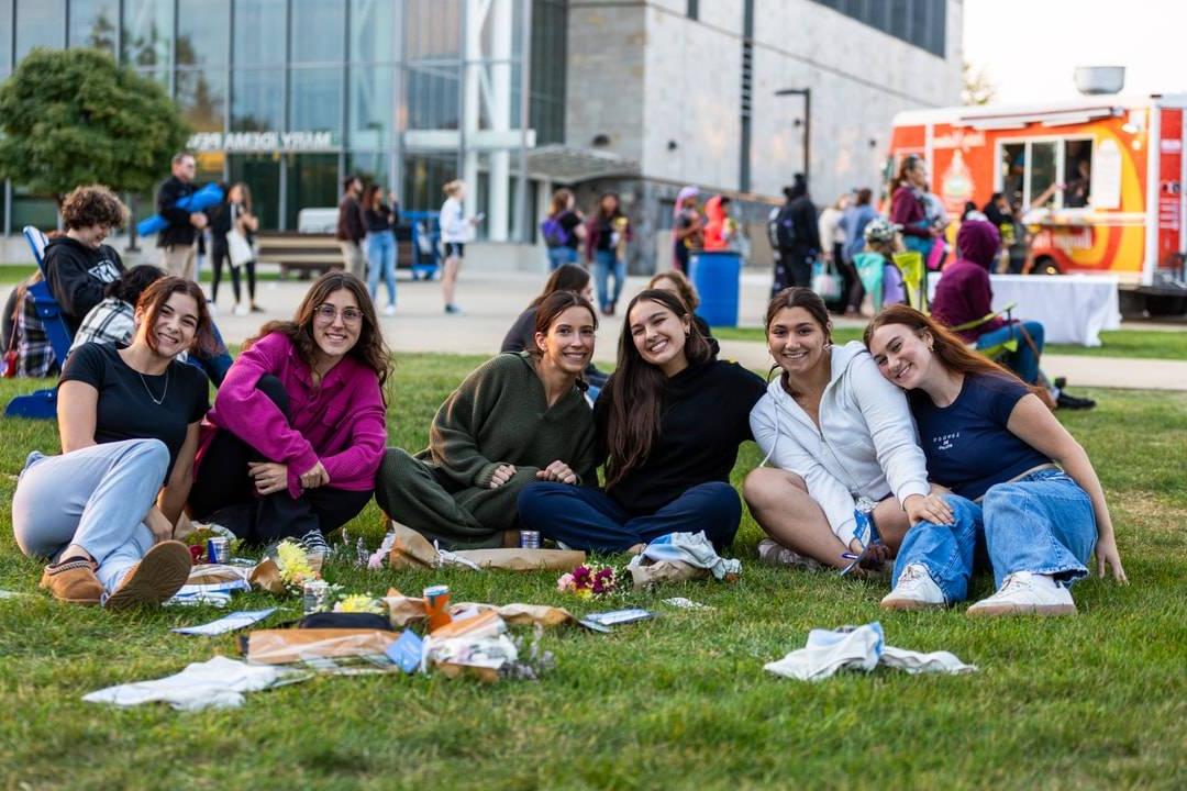 students sitting in the grass smiling